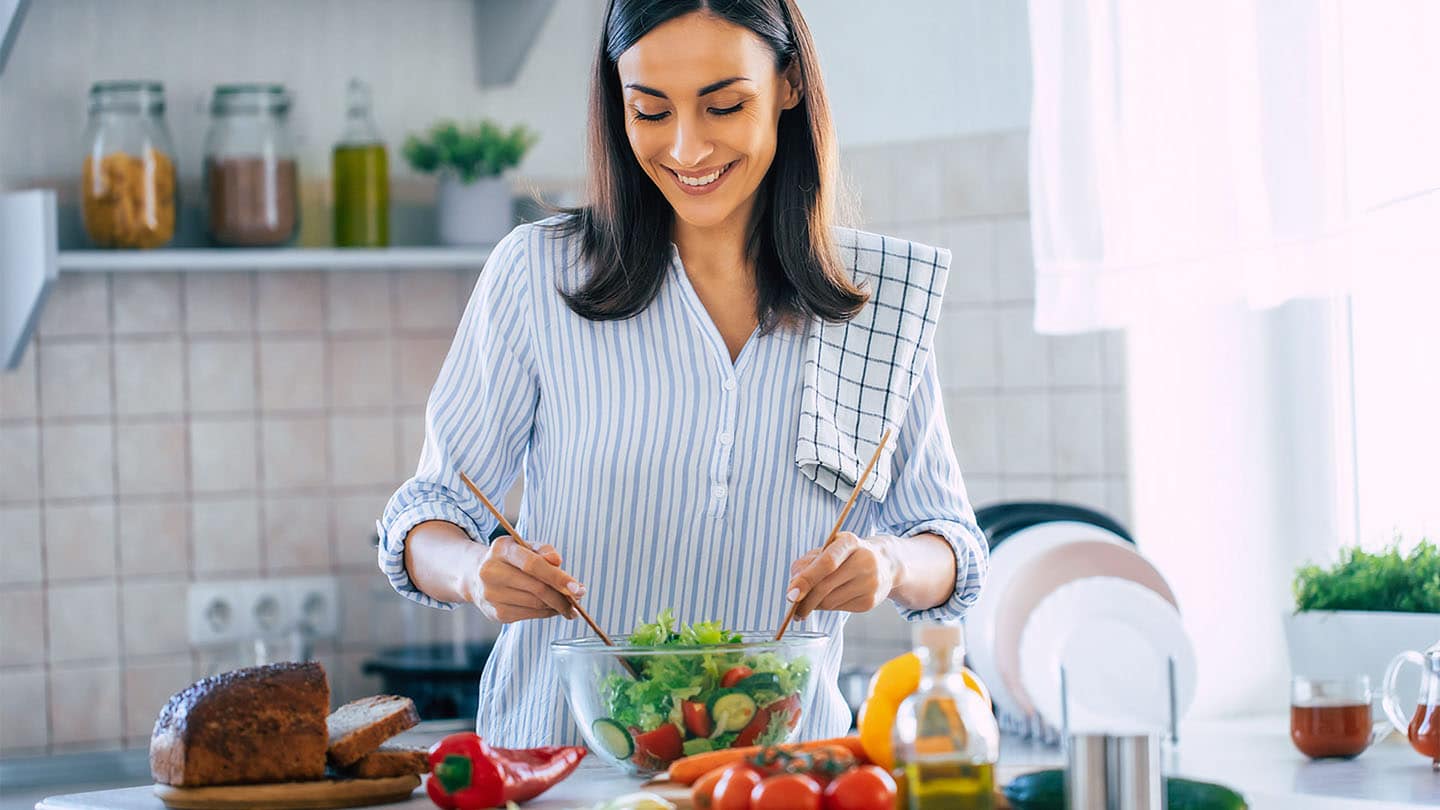 Egy fiatal nő egészséges ételt készít.