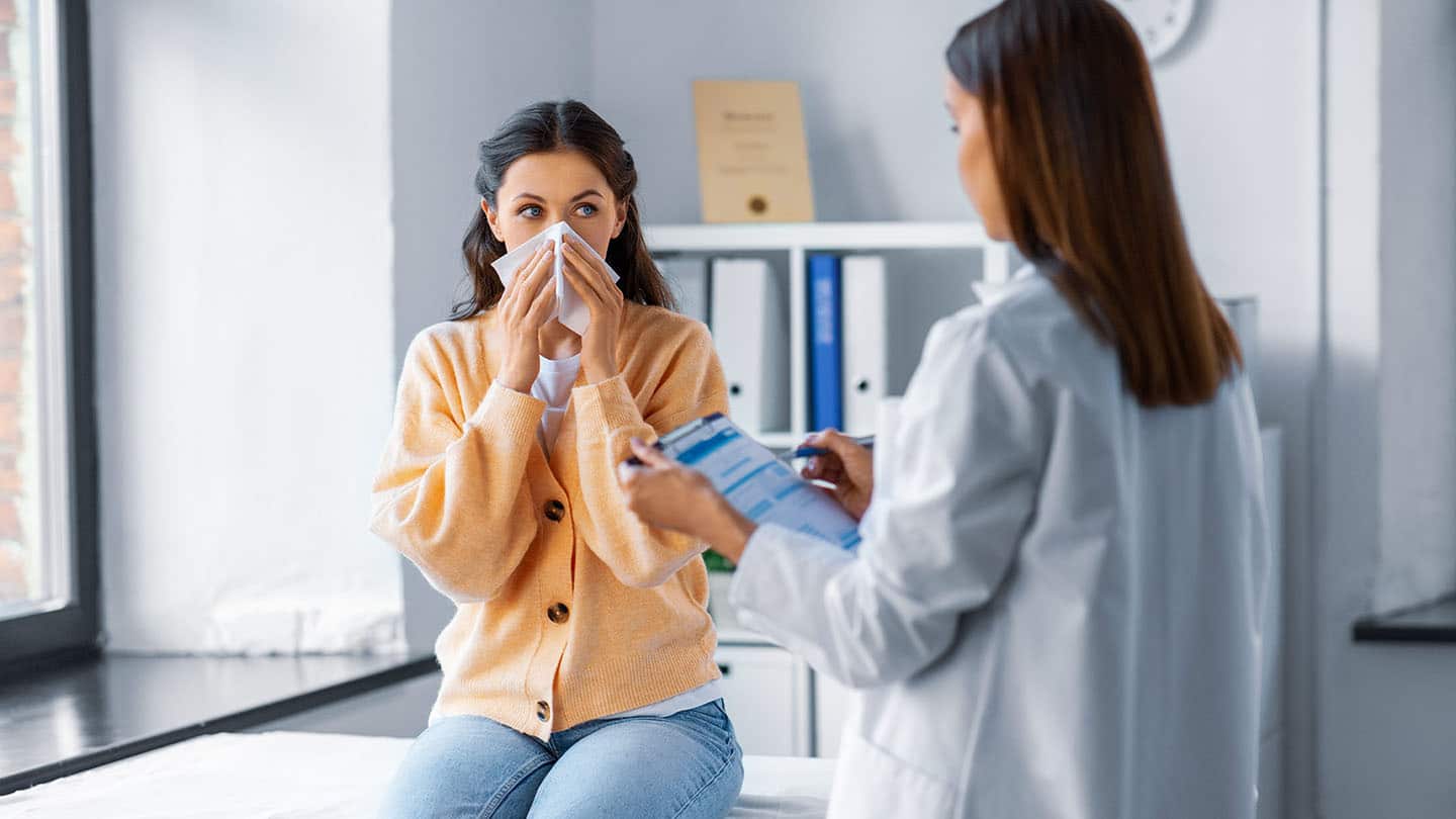 Egy influenzás nőt vizsgál az orvos.