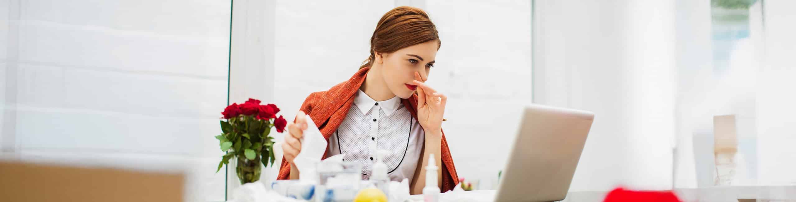 Beteg nő náthával az irodában.