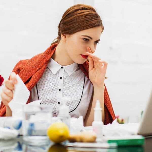 Beteg nő náthával az irodában.