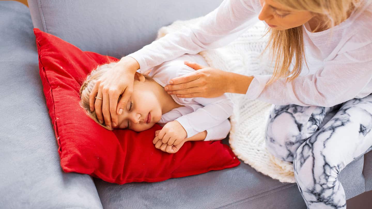 Egy anya megméri beteg gyermeke hőmérsékletét.