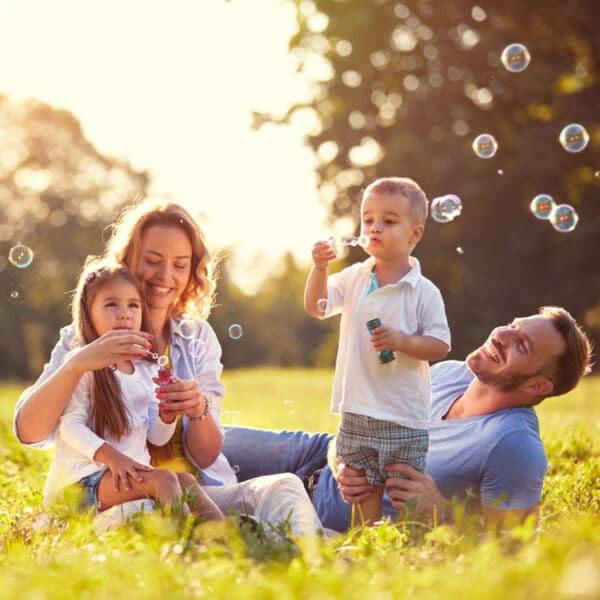 Egy gondtalan, egészséges család játszik a szabadban.