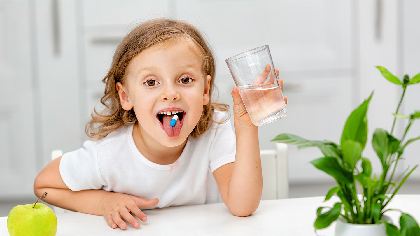 Egy fiatal iskoláslány étrend-kiegészítőt szed az immunitás javítása érdekében.