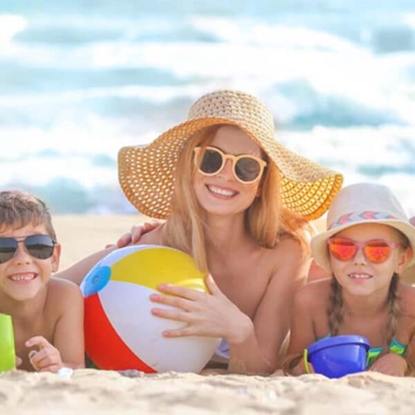 Nyár és a gyermekek betegségei; egy tengerparti család élvezi a strandot és a napsütést.