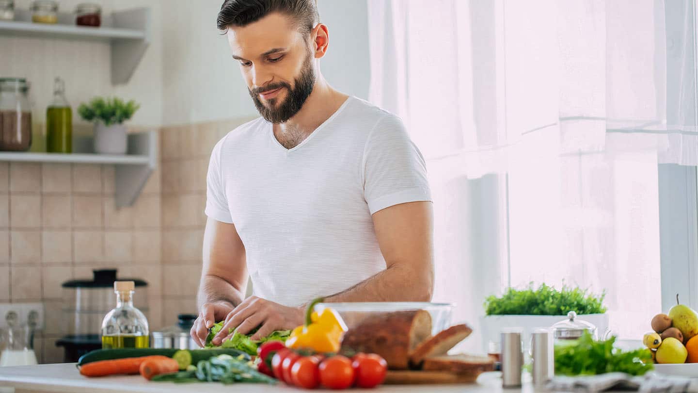 Egy férfi sportoló egészséges ételt készít a konyhában.